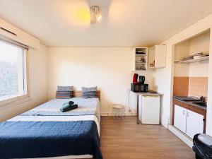 ein kleines Zimmer mit einem Bett und einer Küche in der Unterkunft Studio pour 2 près de la gare in Melun