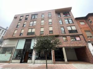 ein hohes Backsteingebäude mit einem Baum davor in der Unterkunft Bierzo Explore in Ponferrada