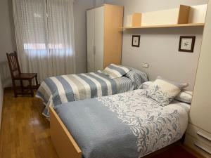 ein Schlafzimmer mit zwei Betten und einem Stuhl in der Unterkunft Bierzo Explore in Ponferrada