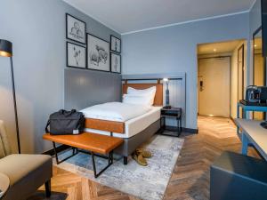 een slaapkamer met een bed, een tafel en een stoel bij Mercure Hotel Dortmund Centrum in Dortmund