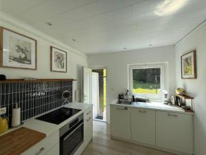 a kitchen with white cabinets and a sink and a window at Chalet Woodyoustay in Theux +14 photos