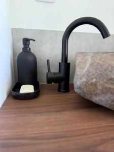 a black soap dispenser next to a bathroom sink at Chalet Woodyoustay in Theux