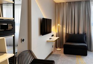 een woonkamer met een stoel en een tv aan de muur bij Holiday Inn - the niu, Coin Frankfurt Ostend by IHG in Frankfurt am Main