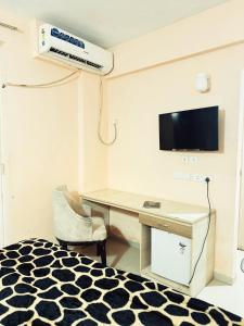 a room with a desk and a tv and a bed at Vrindavan Comfort Stay in Chhatikara