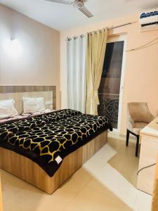 a bedroom with a bed and a window and a chair at Vrindavan Comfort Stay in Chhatikara