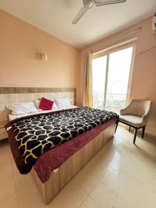 a bedroom with a bed with a chair and a window at Vrindavan Comfort Stay in Chhatikara