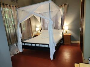 a bedroom with a canopy bed with white sheets at Jangwani Riverview Suits in Mto wa Mbu
