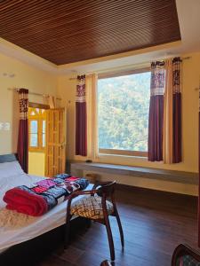 a bedroom with a bed and a large window at Jaibari Basa in Ukhimath