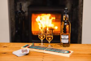 a bottle of wine and two wine glasses on a table at Crossroads Cottage in Drumnadrochit