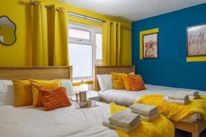 two beds in a room with yellow and blue walls at Open Mind Property- Hot Tub, Sleeps 9 & Free Parking in Portsmouth