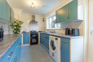 a kitchen with blue cabinets and a washer and dryer at Open Mind Property- Hot Tub, Sleeps 9 & Free Parking in Portsmouth