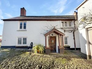 een wit huis met een deur aan een stenen oprit bij Hare and Hounds Exton in Exton