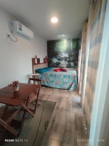 a bedroom with a bed and a table in it at Pousada Mão de Deus in Vila Tepequém