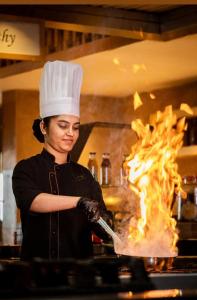 una donna con un cappello da chef sta cucinando sul fuoco di Al Jawahiri Hotel a Erbil Altre 50 foto