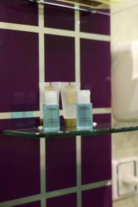 tre candele su una mensola di vetro in un bagno di Arda Golden Hotel Yerevan a Yerevan