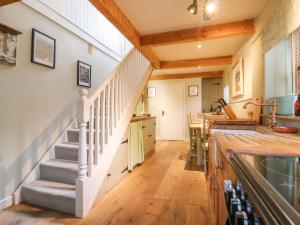 a kitchen with stairs leading up to a kitchen with a counter at The Hayloft - Beautiful Barn Stay in Ashford