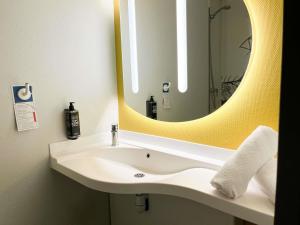 a bathroom with a sink with a large mirror at ibis budget Carcassonne La Cité in Carcassonne