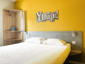 - une chambre avec un lit blanc et un mur jaune dans l'établissement ibis budget Carcassonne La Cité, à Carcassonne