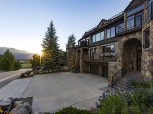 a stone house with a driveway and the sun setting at Luxury By The Lake in Dillon
