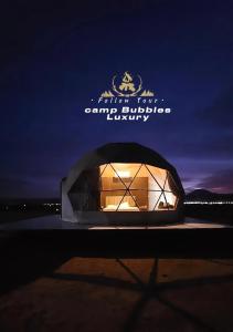 Wadi Rum Bubbles Luxury Camp في وادي رم: مبنى به نافذة مضاءة في الليل
