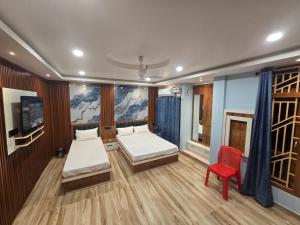 een kamer met 2 bedden en een rode stoel bij Falah Homestay in Bokākhāt
