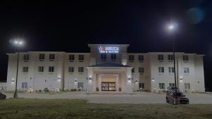 un grande edificio bianco di notte con un parcheggio di Merica Inn & Suites a Wills Point