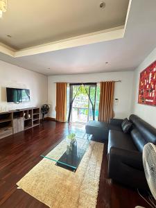 a living room with a black leather couch and a glass table at NS Private Pool villa in Ban Na Kok