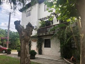 een wit huis met een boom ervoor bij Pousada La Marea in Rio Grande