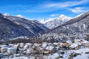 een stad bedekt met sneeuw met bergen op de achtergrond bij Mansarda Panoramica nelle Valli di Lanzo Camino & Silenzio in Ceres