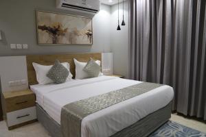 a bedroom with a large bed with white sheets and pillows at اجنحة نزيل in Tabuk