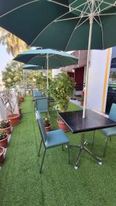 une table et des chaises avec des parasols et des plantes en pot dans l'établissement MM Comfort Inn, à Pondichéry
