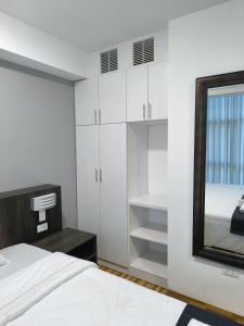 een witte slaapkamer met een bed en een spiegel bij Hotel Belle Maison in Chiclayo