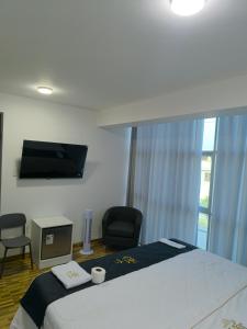 una camera con letto, sedia e TV di Hotel Belle Maison a Chiclayo