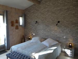 a bedroom with a large bed and a brick wall at Mas Val-Chênaie Gordes in Gordes