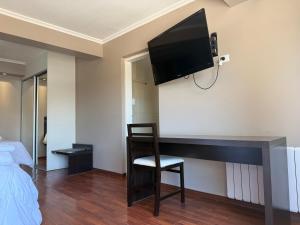 a room with a desk with a television on the wall at Los Lagos Hotel in Sarmiento
