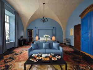 een woonkamer met een blauwe bank en een tafel met eten erop bij Jules César Hotel & Spa Arles - MGallery Collection in Arles