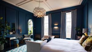 a bedroom with blue walls and a bed and a chandelier at Wren Place Hall in Barnsley