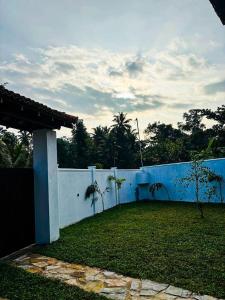 een wit hek met palmbomen in een tuin bij Legacy Weligama in Weligama +35 foto's