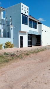 a white house with black doors and a dirt road at Cuarto Privado in Arandas