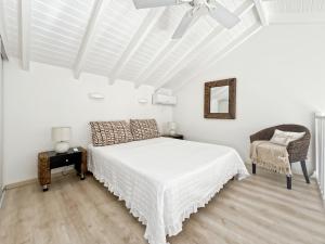 a white bedroom with a bed and a chair at Mango Vert Duplex - Orient Bay in Saint Martin