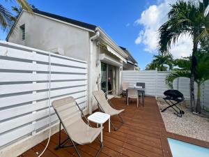 a patio with chairs and a white fence and palm trees at Mango Vert Duplex - Orient Bay in Saint Martin