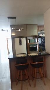 eine Küche mit einer Theke und 2 Hockern in der Unterkunft Lar Sousa Rocha in Capão da Canoa