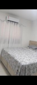 Bett in einem Zimmer mit weißen Vorhängen in der Unterkunft Lar Sousa Rocha in Capão da Canoa