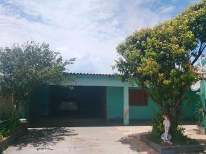 een groen huis met een auto ervoor geparkeerd bij Kitnet com garagem e Wi-Fi in Tramandaí