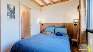 a bedroom with a blue bed with a wooden headboard at Buron St Roch in Murol