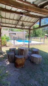een groep banken gemaakt van boomstronken onder een pergola bij Casa en complejo in San Roque