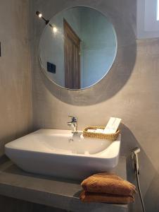 een badkamer met een wastafel en een ronde spiegel bij LUSSO Mirissa in Mirissa
