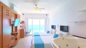 a bedroom with a bed and a tub and a television at Suite Sol in Cancún