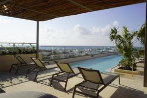 een groep stoelen op een patio met een zwembad bij Hotel Indigo Playa del Carmen by IHG in Playa del Carmen