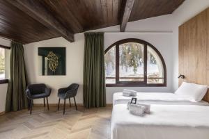two beds in a room with a window and two chairs at B&B Hotel Passo Tre Croci Cortina in Cortina dʼAmpezzo